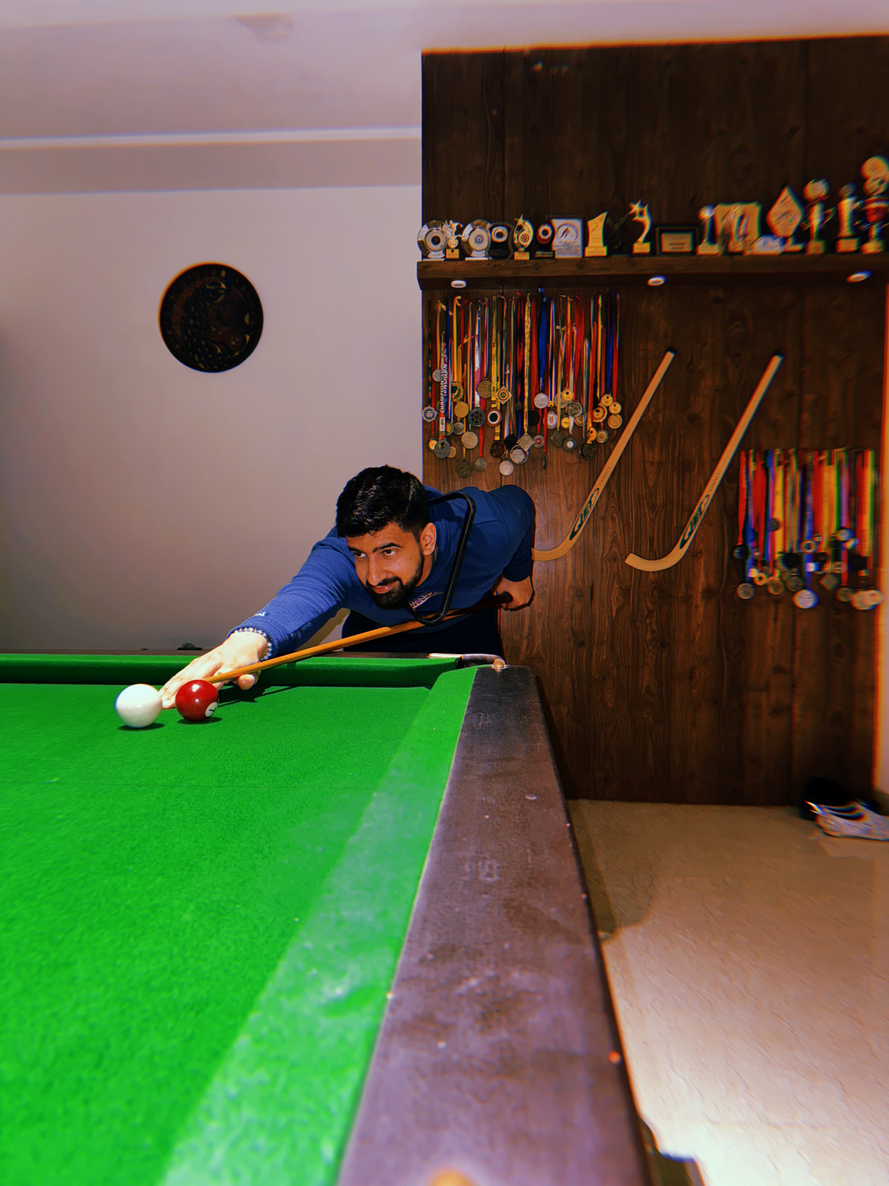 Parth playing pool in front of the medal wall